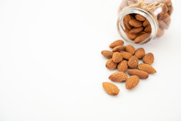 Glass jar with almond on white background.