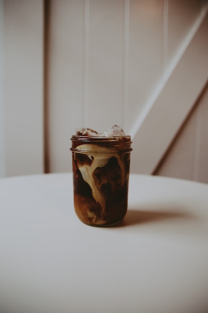 Glass jar with coffee Glasse with cream in it on a white table