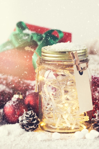Glass jar with lights and christmas decorations with snow around