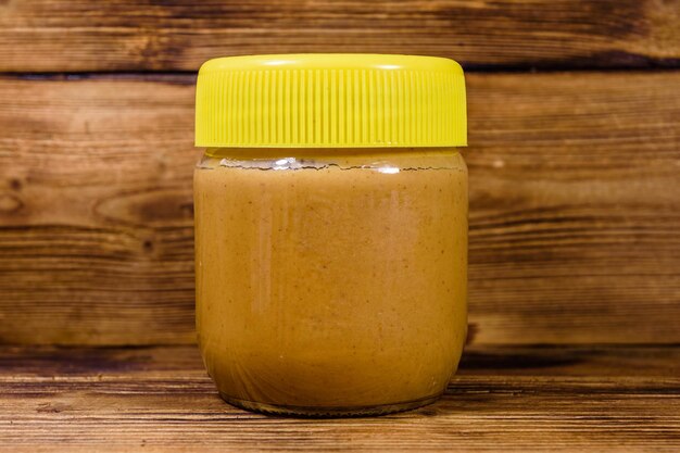 Glass jar with peanut butter on a wooden table