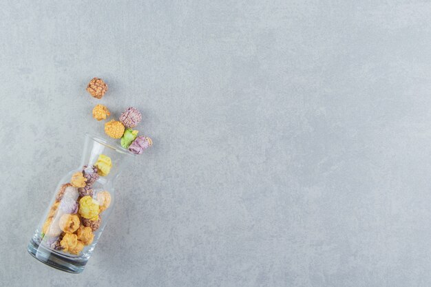 A glass jug of sweet multicolored popcorn . 