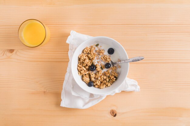 Glass of juice; bowl of healthy oatmeal with blueberries on wooden surface