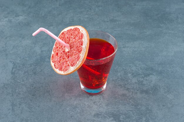 Glass of juice decoratively fitted with a slice of grapefruit on marble background. High quality photo