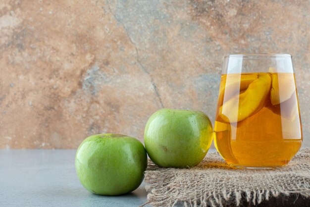 Glass of juice and fresh apples on burlap.