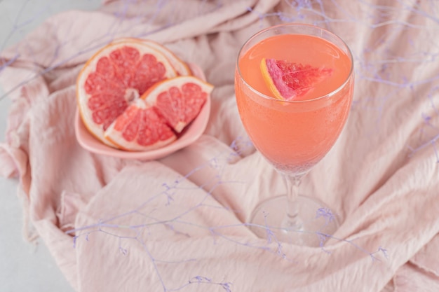 A glass of juice and fresh grapefruit on pink cloth