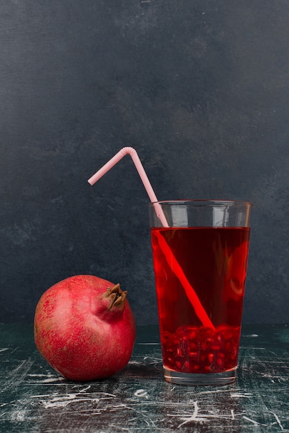 Glass of juice and pomegranate on marble table