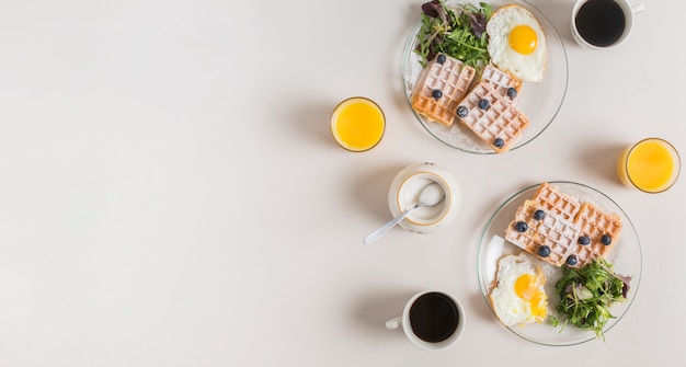 주스의 유리; 분유; 흰색 배경 위에 접시에 와플과 튀긴 계란 차와 건강 샐러드