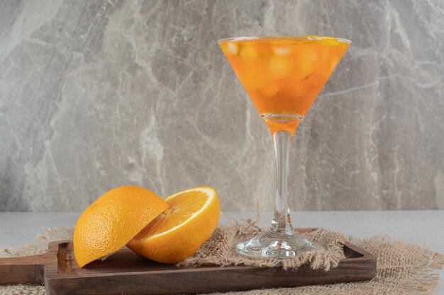 A glass of juice with citrus fruits on wooden board