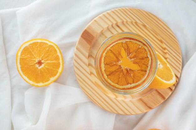 A glass of juice with fresh oranges on wooden plate