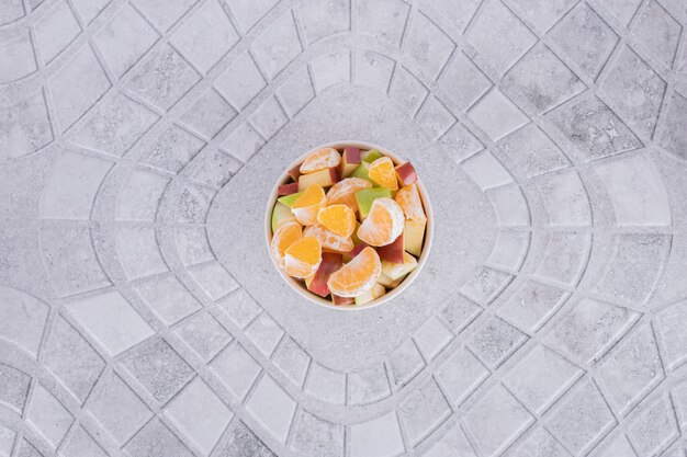 A glass of juice with fruit slices on marble background.