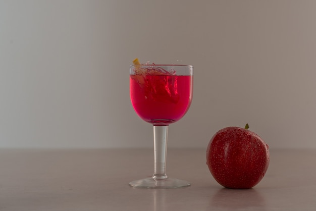 Glass of juice with red apple .