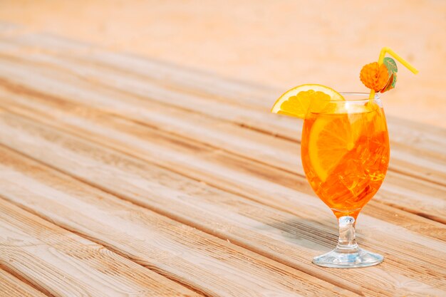 Glass of juicy orange drink on wooden table