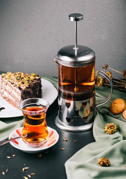 Glass kettle, glass of tea with a slice of cake.