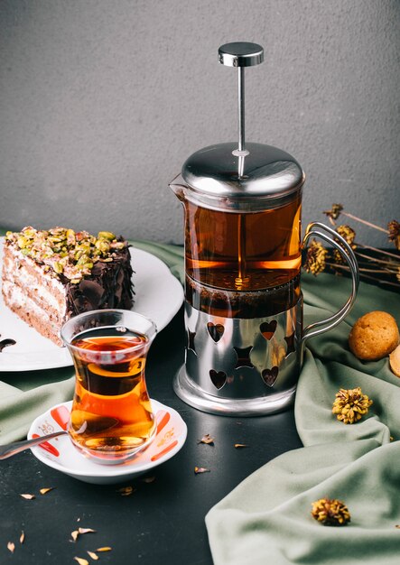 Glass kettle, glass of tea with a slice of cake.