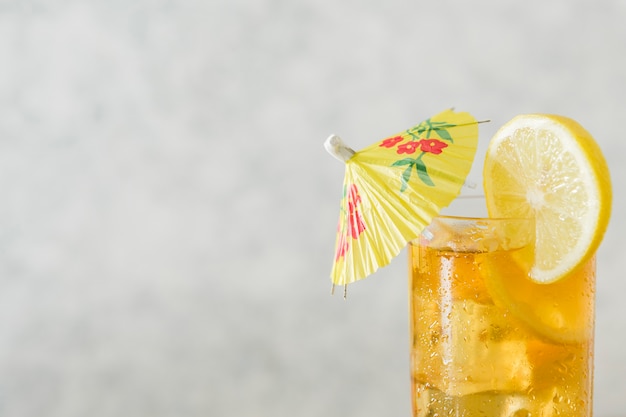 Free photo glass of lemon drink with umbrella and copy space