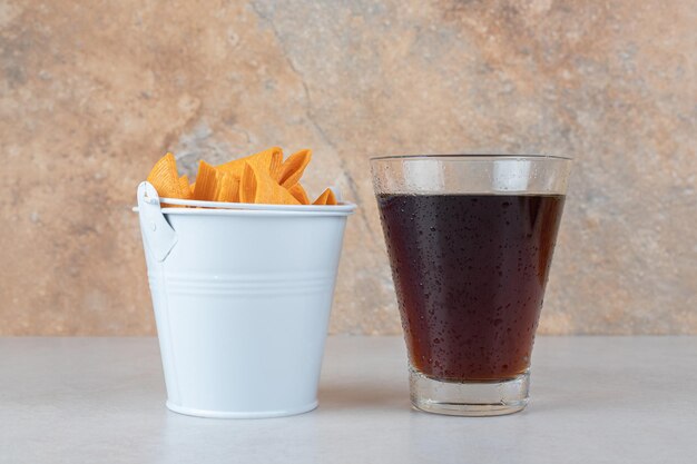 Glass of lemonade and bucket of triangle shaped chips. 