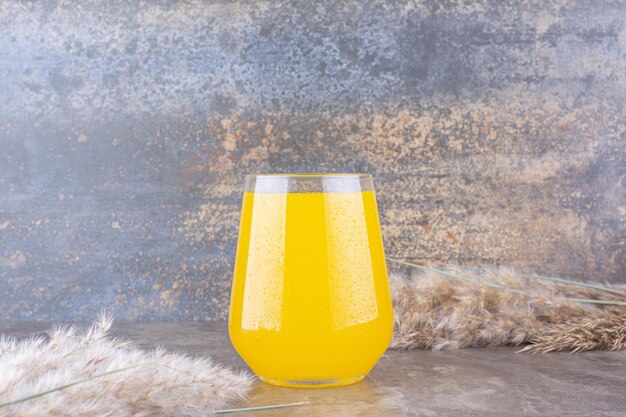 Glass of lemonade with ears of wheat on marble table. High quality photo