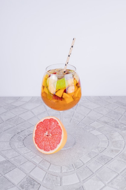 Glass of lemonade with slice of grapefruit and straw .