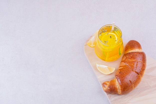 A glass of lemonade with sweet buns on white platter.