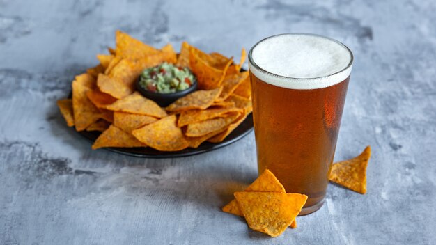 Glass of light beer on white stone surface. Cold alcohol drink and snacks are prepared for a big friend's party.