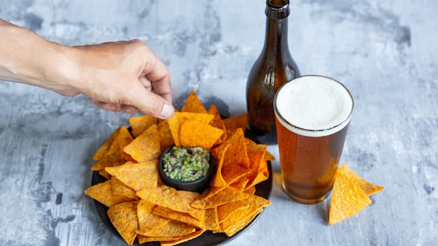 Glass of light beer on white stone wall. Cold alcohol drink and snacks are prepared for a big friend's party.