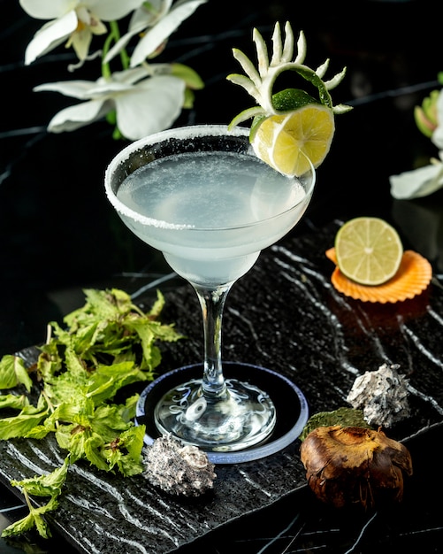 Bicchiere di cocktail al lime guarnito con fetta di lime e scorza