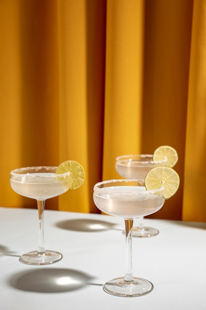 Glass of margarita cocktail garnish with lime on table against yellow curtain