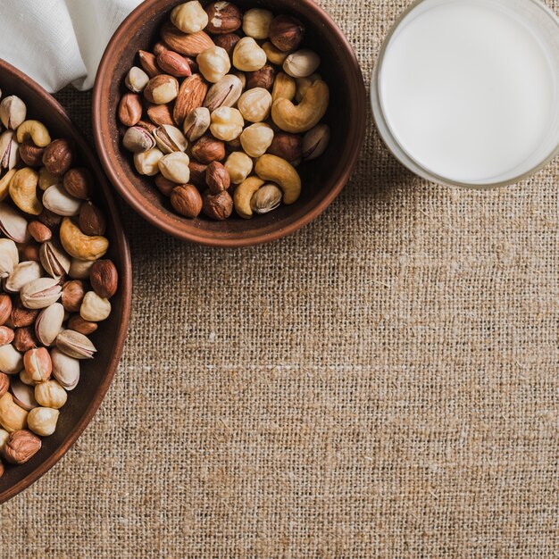 Glass of milk near bowls with nuts