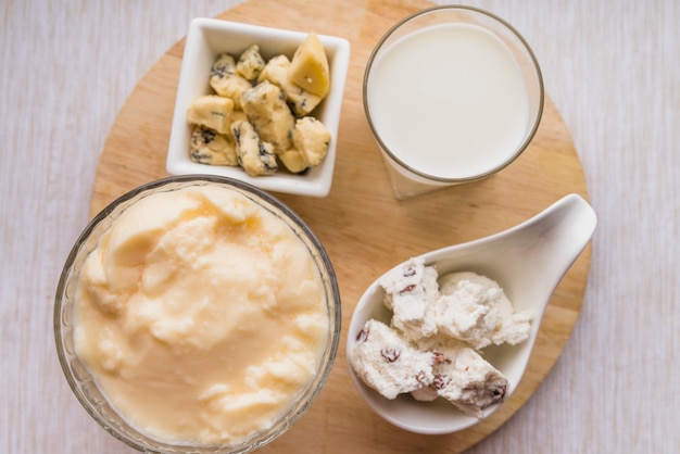 Glass of milk near plates with set of tasty cheese