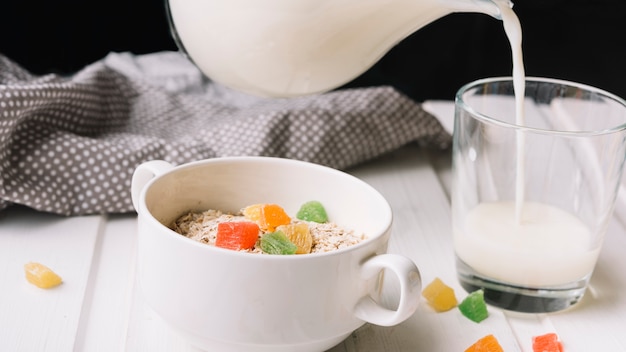 Glass of milk and oatmeal with jelly candies on table