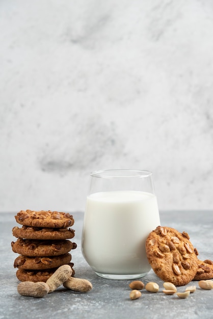 Glass of milk and stack of cookies with honey on marble table. 