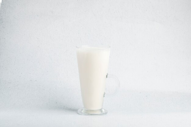 A glass of milk in a white baclground with small shade.