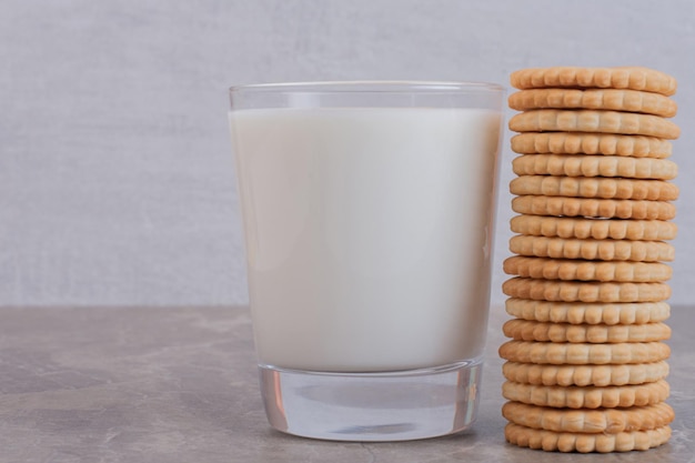 A glass of milk with cookies on white table