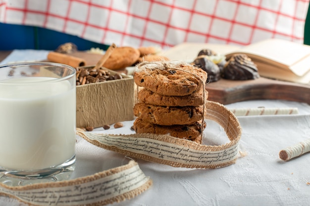 A glass of milk with oatmeal cookies around