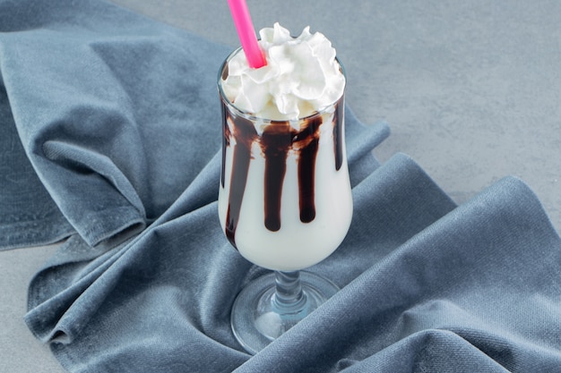 A glass of milkshake next to the towel , on the marble background. High quality photo