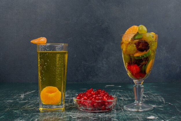 Glass of mixed fruits, juice and pomegranate seeds on marble table