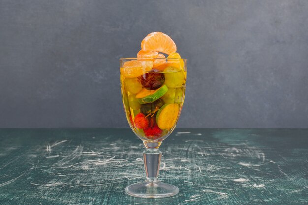 Glass of mixed fruits on marble table.