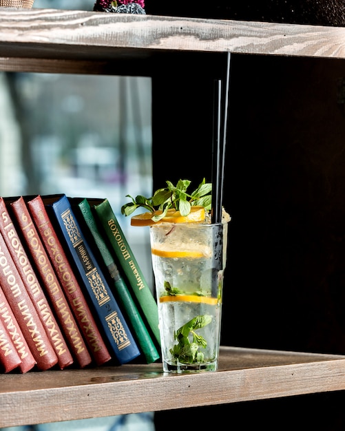 Foto gratuita un bicchiere di mojito posto accanto ai libri