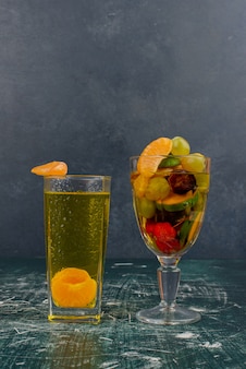 Стакан смешанных фруктов и мандаринового сока на мраморном столе