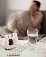 Бесплатное фото Стакан воды и таблетки с размытым больным человеком