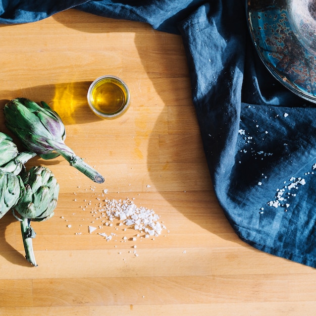 Foto gratuita bicchiere d'olio vicino a carciofi e sale