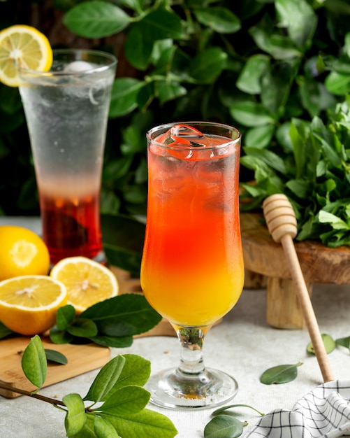 A glass of ombre cocktail served with ice cubes