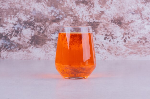 大理石の上のオレンジ色の飲み物のガラス。