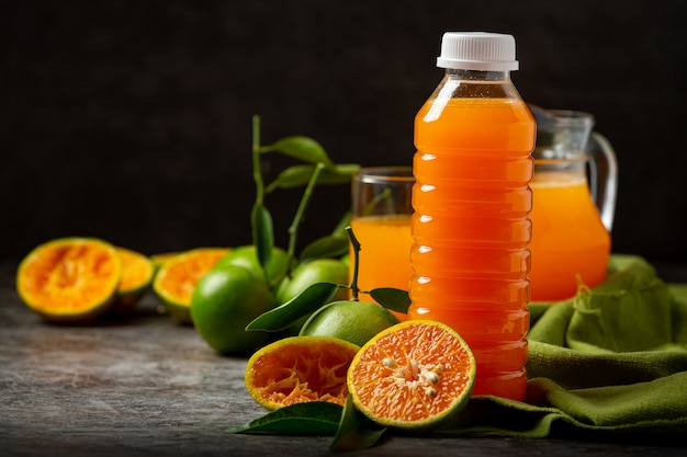 Un bicchiere di succo d'arancia e frutta fresca sul pavimento con cubetti di ghiaccio.