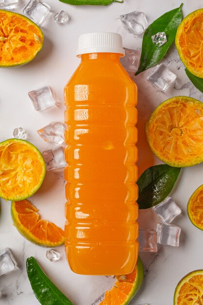 A glass of orange juice and fresh fruit on the floor with ice cubes.