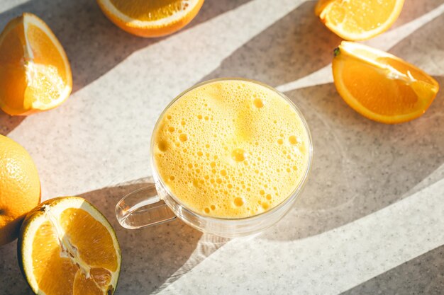 A glass of orange juice and fruit halves of oranges on the kitchen table
