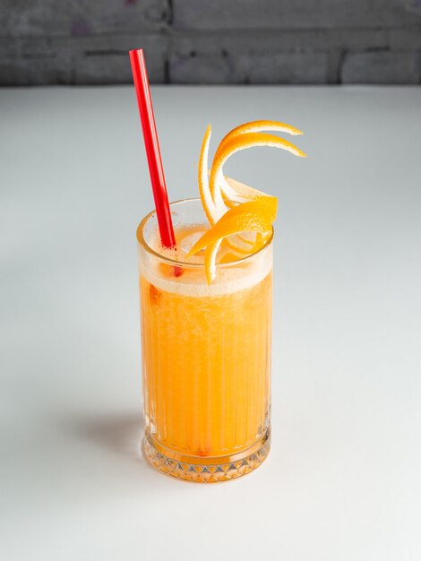 A glass of orange juice garnished with orange zest