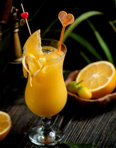 A glass of orange juice garnished with orange zest