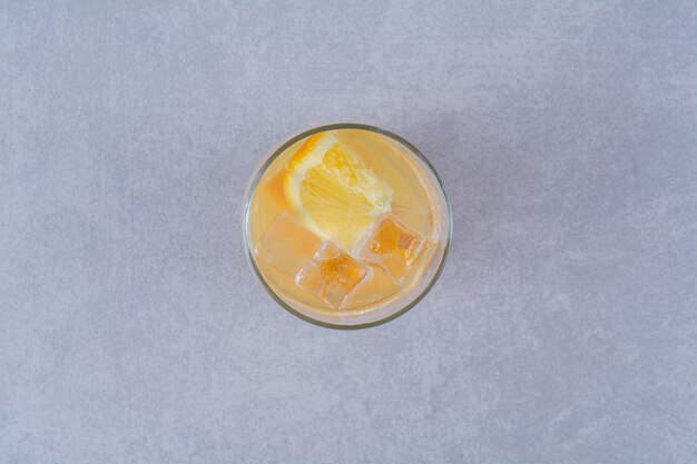 A glass of orange juice on marble table.