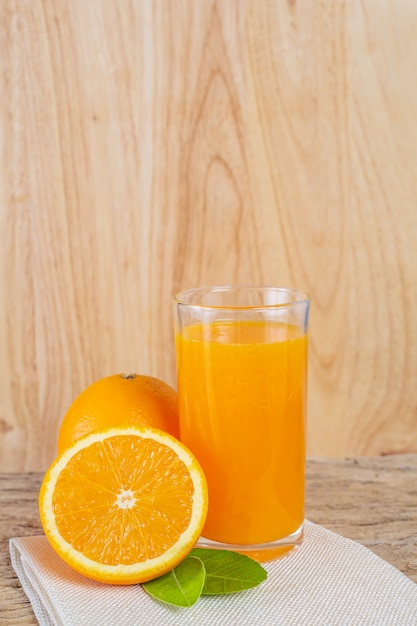 Glass of orange juice placed on wood.